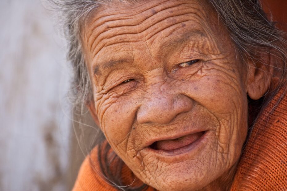 Alte Frau lächelt mit faltigem Gesicht.