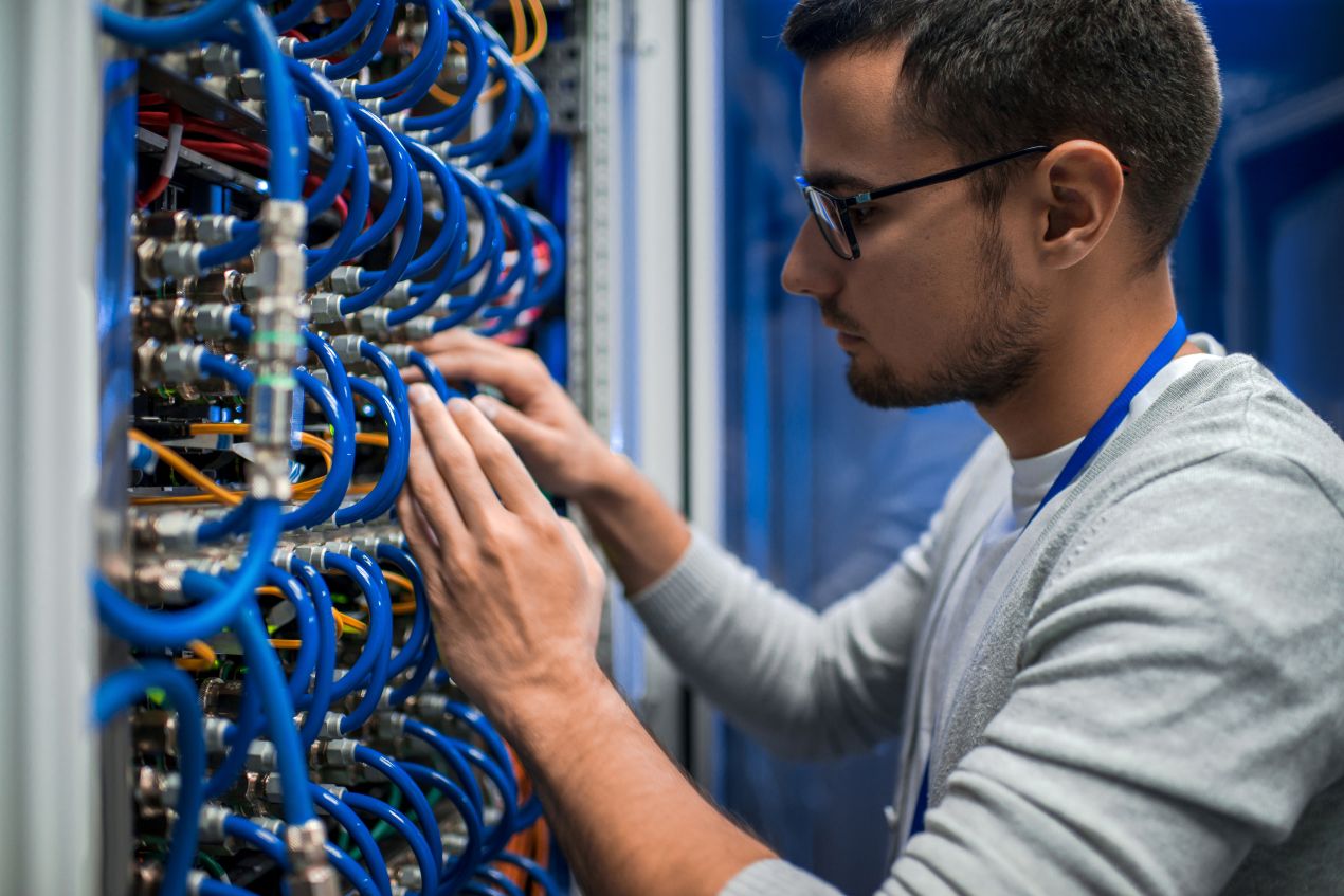Mann installiert LWL Patchkabel in einem professionellen Netzwerkschrank